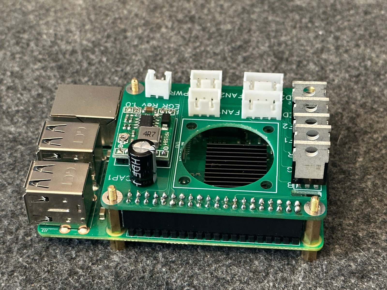 Populated green PiLED HAT mounted on a Raspberry Pi, with white connectors, a voltage converter, capacitor and five metal power devices.